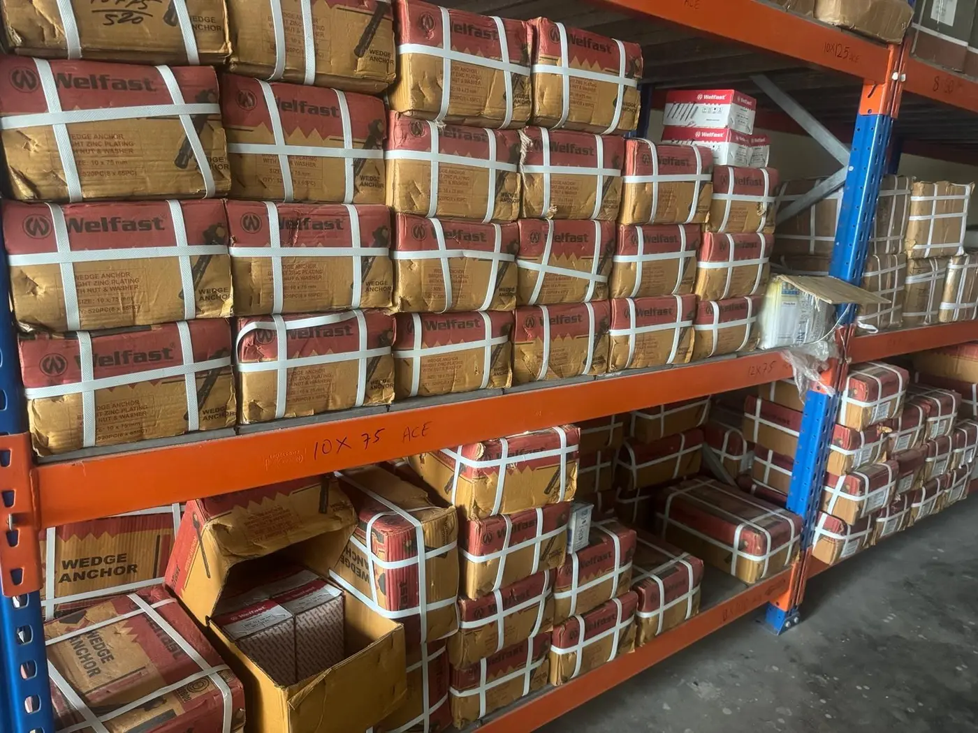Shelves of boxed wedge anchors at the Bengaluru warehouse, bays marked 10 x 75 and 10 x 125
