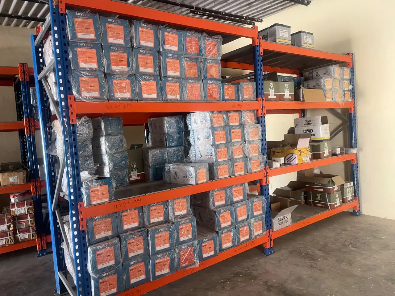 Cartons of self drilling hex screws on racking, hand-labelled by size